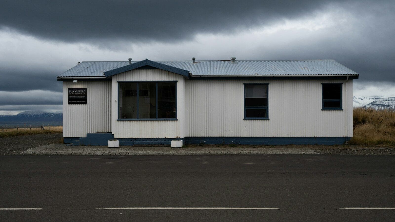 A white house sits under a stormy, grey sky